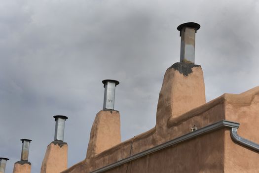 Row of chimneys on adobe building in Old Town district of Albuquerque, New Mexico.  Copy space in sky above architectural details. 