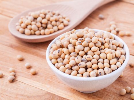 Close Up soy beans in wooden spoon and bowl on wooden background.