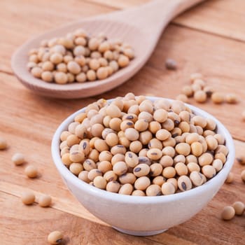 Close Up soy beans in wooden bowl and spoon on wooden background.