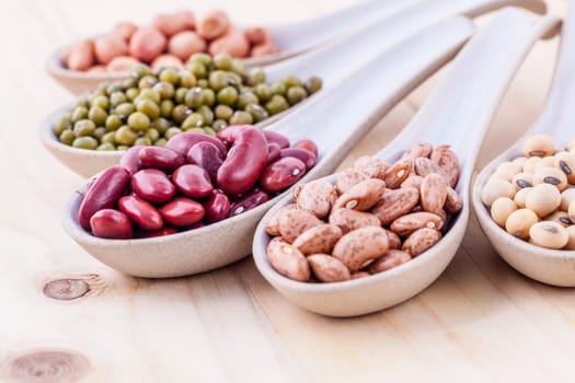 Assortment of beans and lentils in wooden spoon on wooden background. mung bean, groundnut, soybean, red kidney bean , black bean ,red bean and brown pinto beans .