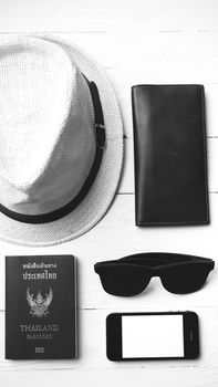 hat sunglasses smart phone and passport over white table black and white color