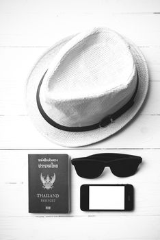 hat sunglasses smart phone and passport over white table black and white color