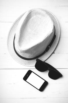 hat sunglasses and smart phone on white table black and white color