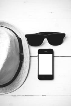 hat sunglasses and smart phone on white table black and white color