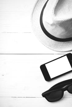 hat sunglasses and smart phone on white table black and white color