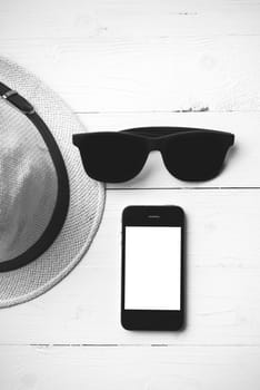 hat sunglasses and smart phone on white table black and white color