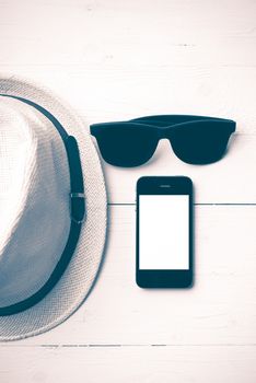 hat sunglasses and smart phone on white table vintage style