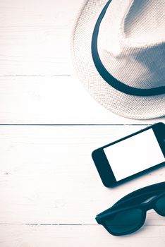 hat sunglasses and smart phone on white table vintage style