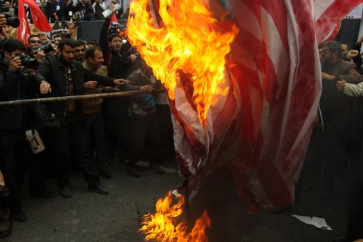 IRAN, Tehran: Protesters burn a flag of the US as hundreds of people march in front of the former US embassy in Tehran, during the '13 Aban' (4th of November in english), on November 4, 2015, to commemorate the anniversary of the 1979 US embassy taking.