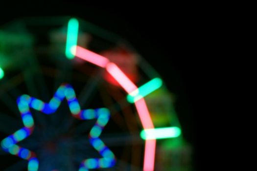 Defocused and blurred image of ferris wheel at amusement park at night for background usage.
