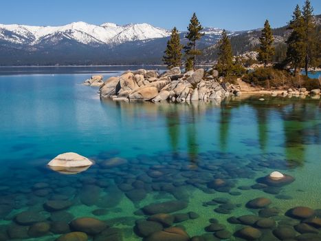 Scenic view of beautiful Lake Tahoe in Spring, landscape of the United States of America, clear water, nice sky,  stone island, tree, fresh air and snow mountains