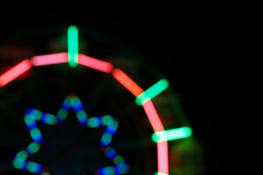 Defocused and blurred image of ferris wheel at amusement park at night for background usage.