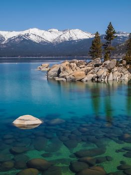 Scenic view of beautiful Lake Tahoe in Spring, landscape of the United States of America, clear water, nice sky,  stone island, tree, fresh air and snow mountains