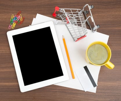 Tablet with blank paper and coffee on wooden table