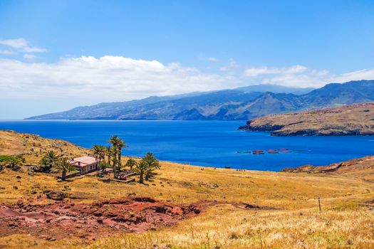 Mountainous landscape / lonely house / ranch with palms - peninsula Ponta de Sao Lourenco - east of Madeira. Airport in the background