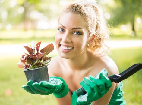 Smiling young woman planting flowers in the garden.