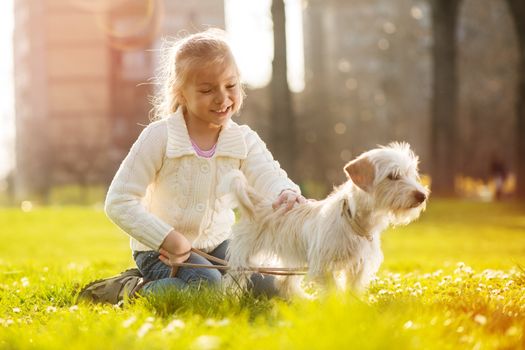 Little girl relaxing with her puppy dog in the park