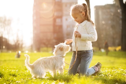 Little girl playing with her puppy dog in the park