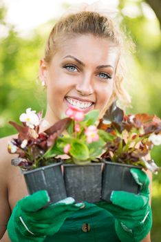 Smiling young woman planting flowers in the garden.