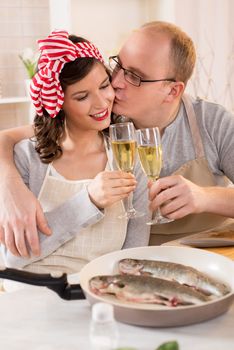 Couple preparing dinner in a kitchen and enjoying in a champagne