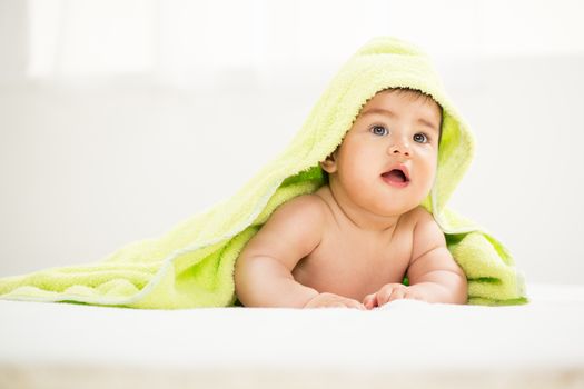 Cute baby boy lying under a towel