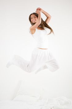 Cute young beautiful girl at morning jumping on the bed