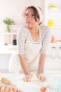 Conceived young woman making dough in the kitchen
