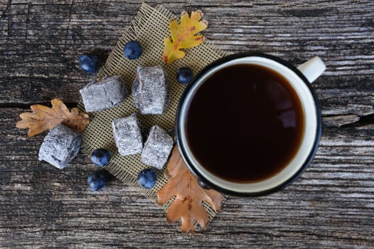 Romantic autumn still life with cookies, cup of tea, blackthorn berries and leaves at wooden board, top view