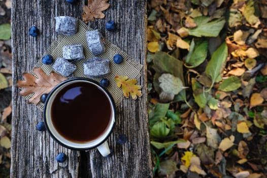 Romantic autumn still life with cookies, cup of tea, blackthorn berries and leaves at wooden board, top view