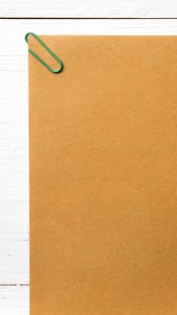 brown paper with green paper clip over white table