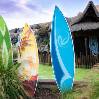 Colorful surfboards in front of a typical Hawaiian hut.