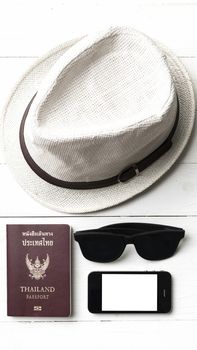 hat sunglasses smart phone and passport over white table