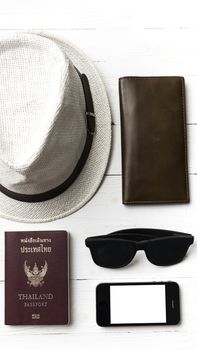 hat sunglasses smart phone and passport over white table