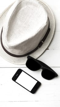 hat sunglasses and smart phone on white table