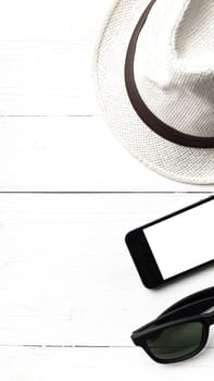 hat sunglasses and smart phone on white table