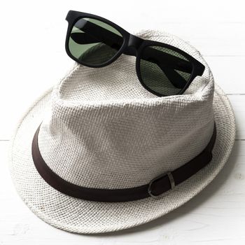 hat and sunglasses on white table