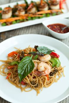 Thai food dishes with shrimp and noodles with scallops in the background. Shallow depth of field. 