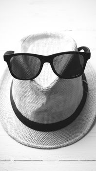 hat and sunglasses on white table black and white color