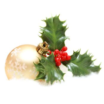 An isolated shot of a Christmas bauble and some holly decor.