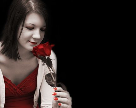 A beautiful woman dreams passionately as she glances at her red rose in this artisticly toned image.