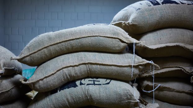 stack of burlap sacks with coffee beans at warehouse