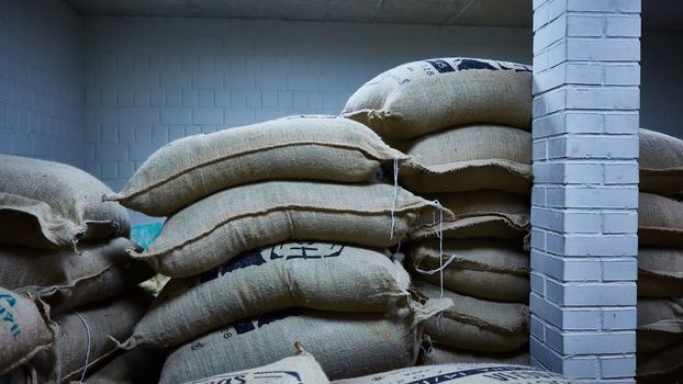 stack of burlap sacks with coffee beans at warehouse