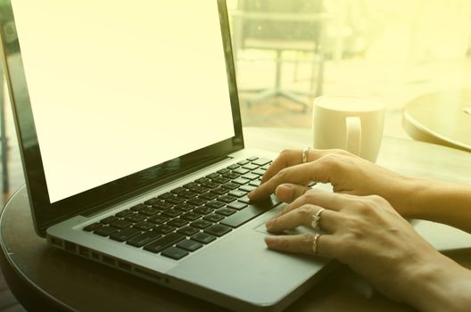 Close up of business woman hand working on laptop computer on wooden desk as concept with overcast effect