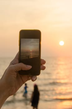 woman hands holding mobile phone at sunset