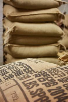 stack of burlap sacks with coffee beans at warehouse