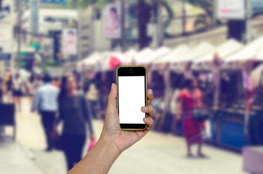 Female hand holding mobile smart phone on people blur background, vintage style