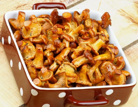Delicious Roasted Golden Chanterelles in Brown Polka Dot Bowl Cross Section on Wooden background