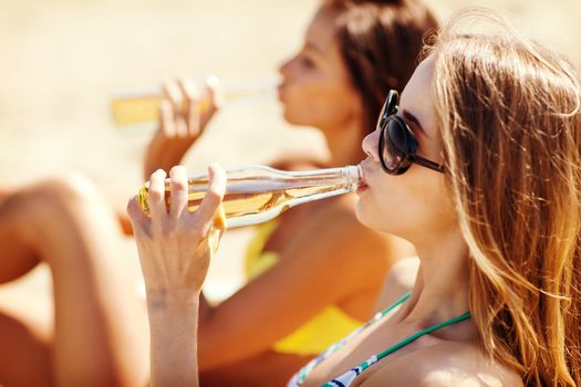 summer holidays and vacation - girls in bikinis with drinks on the beach chairs