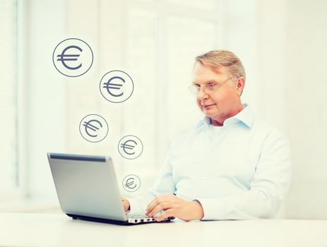 technology, oldness and lifestyle concept - old man in eyeglasses working with laptop computer at home