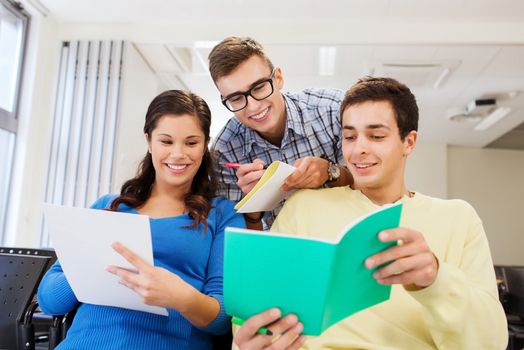 education, high school, teamwork and people concept - group of smiling students with notepads sitting in lecture hall